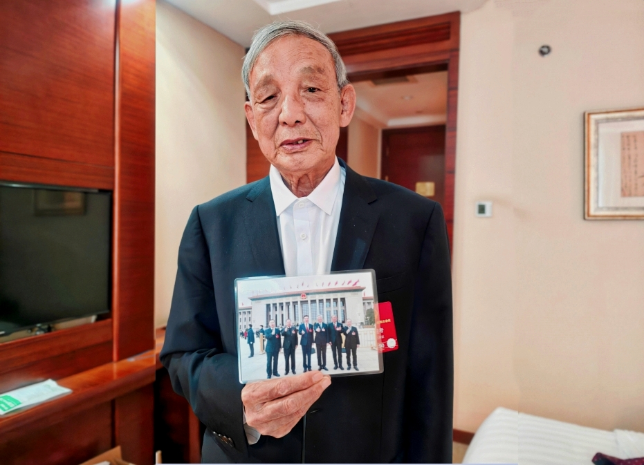 郭进考向记者介绍2024年全国两会期间6位小麦育种专家的合影。人民网记者 黄盛摄