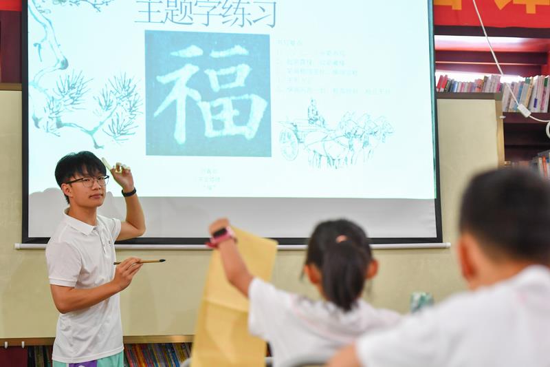 △2024年8月7日，在湖南長沙望城區月亮島街道黃都港社區，志願者在給小朋友上書法課。